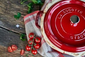 Staub Round Cocotte 24 cm Cherry Red in a kitchen setting, showcasing its elegant design and versatility.